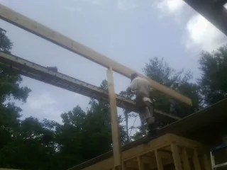 Carpenter setting a ridge beam over a new addition frame — Ice Dam Removal by Roofing Brothers in Wilber