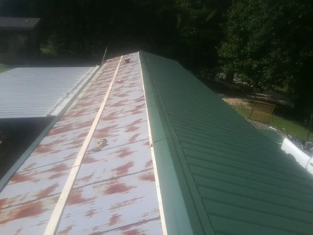 Old rusted panels beside newly installed green metal roofing — Wind Damage Roof Repair by Roofing Brothers in Wilber