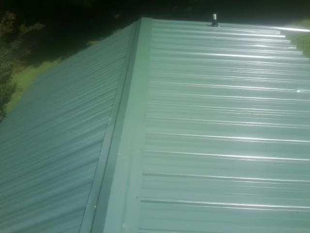 New green metal panels meeting at the ridge of a roof — Flat Roof Repair work by our crew in Wilber
