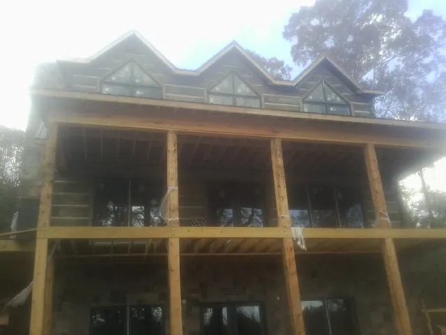 Dormers and porch framing on a large log home under construction — Roof Coating work by our crew in Wilber
