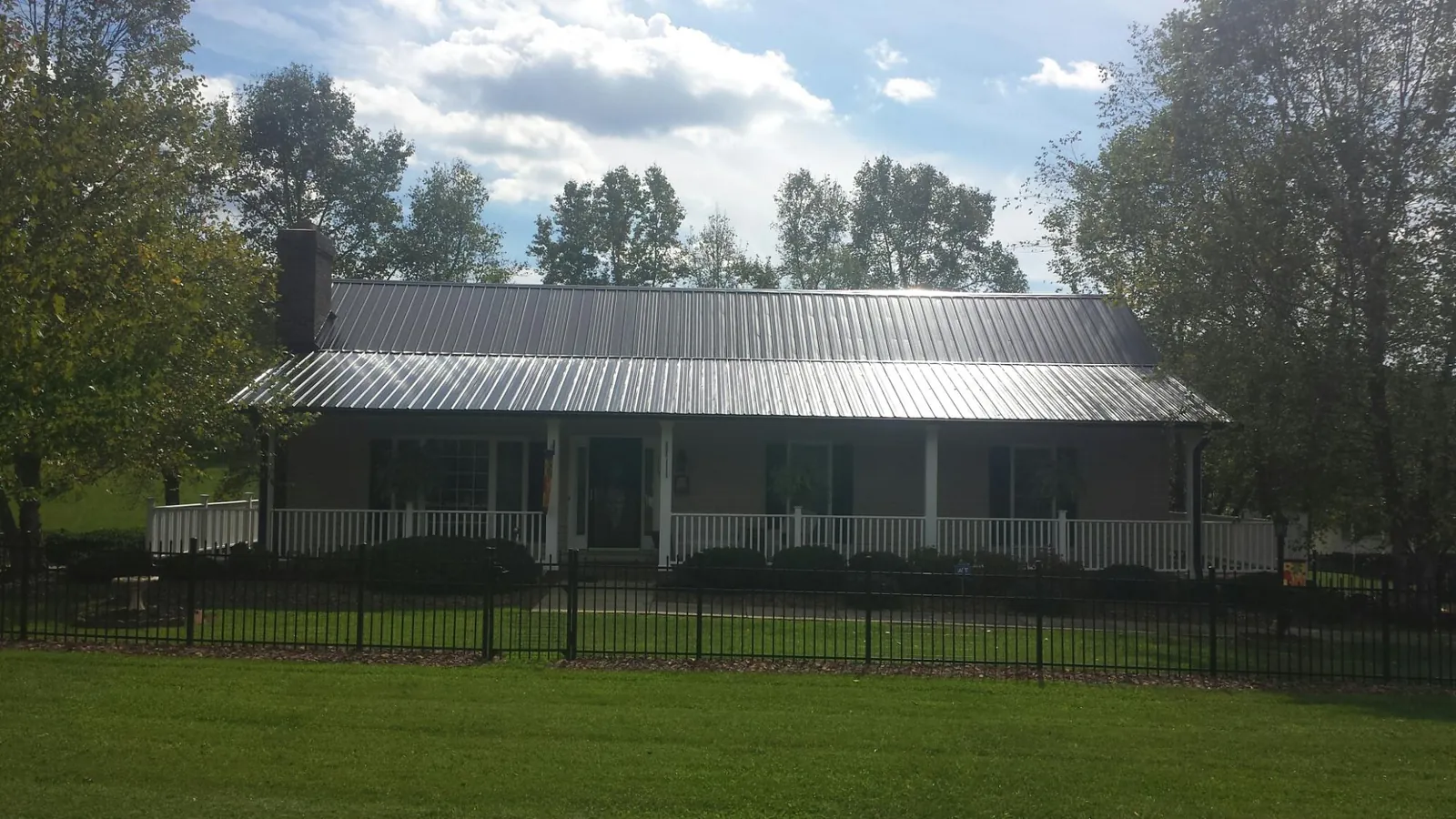 Gray metal roof on a brick ranch with a full width front porch — Gutter Guard Installation work by our crew in Wilber